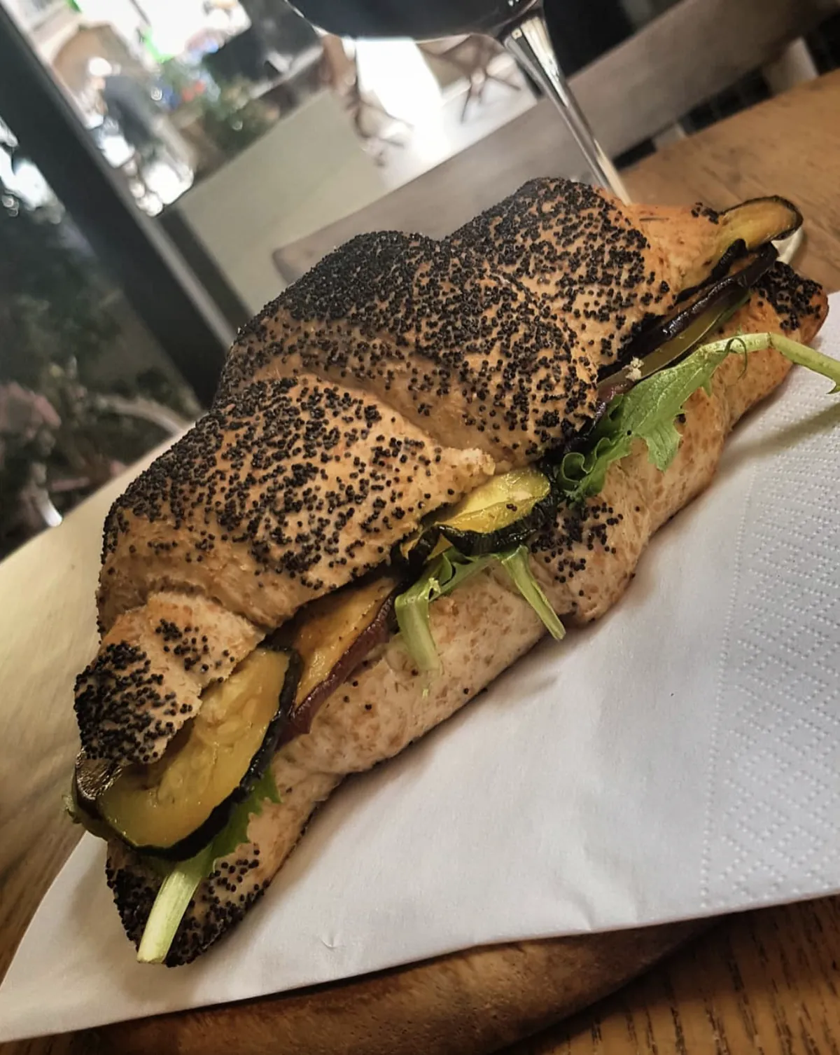 Panino lungo al pane con semi di papavero, farcito con zucchine e melanzane grigliate e insalata.